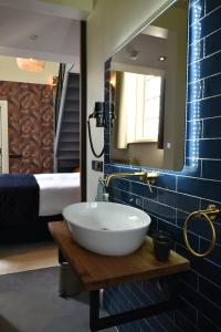 a bathroom with a sink and a mirror and a bed at Kerkhotel Bij De Pastorie in Reitsum