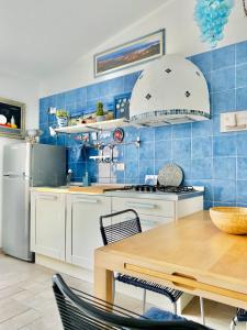 a kitchen with a table and a blue tiled wall at Appartamento panoramico in La Maddalena +8 photos