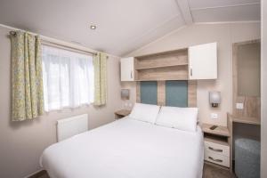 a bedroom with a white bed and a window at Killigarth Manor Holiday Park in Polperro