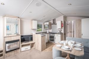 a kitchen and living room with a table and chairs at Killigarth Manor Holiday Park in Polperro