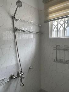 y baño con ducha y pared blanca. en Newly built house in Accra, en Danfa