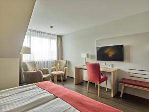 ein Hotelzimmer mit einem Bett, einem Schreibtisch und Stühlen in der Unterkunft Restaurant & Hotel Heidelberg in Aadorf