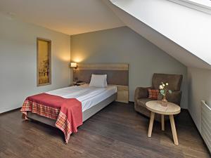 ein Hotelzimmer mit einem Bett und einem Stuhl in der Unterkunft Restaurant & Hotel Heidelberg in Aadorf