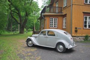 een oude auto geparkeerd voor een gebouw bij Kirjakkalan Ruukkikylä in Teijo