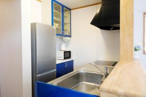 una cocina con fregadero de acero inoxidable y armarios azules en Bello House Imabari en Imabari