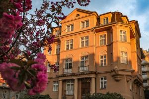 a large orange building with windows and pink flowers at Villa Wingolf in Karlovy Vary
