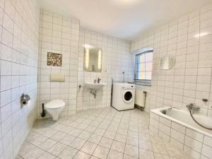 a white tiled bathroom with a sink and a toilet at Wanderurlaub mit Hund in Harra