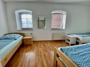 een slaapkamer met 2 bedden, een bureau en 2 ramen bij Wanderurlaub mit Hund in Harra