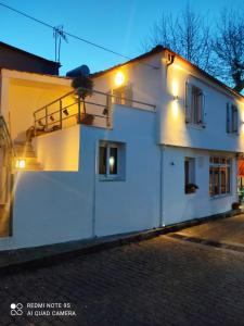 Un bâtiment blanc avec des lumières sur son côté dans l'établissement Plane Tree House, à Próti