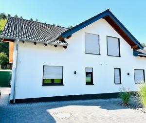 a white house with windows and a roof at Traumferienhaus Leimbach am Nürburgring in Leimbach