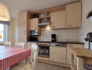 eine Küche mit weißen Schränken und einem Tisch mit einem roten Tisch in der Unterkunft Haus am Meer 63 in Kaltenhof