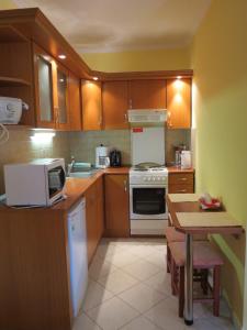 a kitchen with wooden cabinets and a table with a microwave at Jázmin Apartman in Harkány