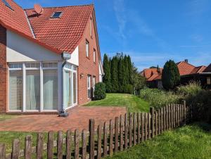 een rood bakstenen huis met een houten hek bij Haus Christof - Hooksiel in Wangerland