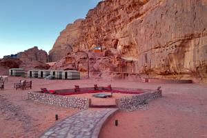 a group of benches in a desert with a cliff at Magic Bedouin Star in Wadi Rum