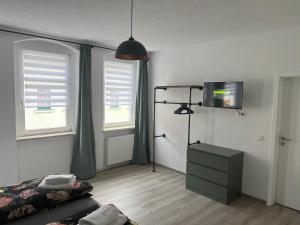 een woonkamer met een bed, een tv en 2 ramen bij Gästehaus Graupner-Hainichen in Hainichen