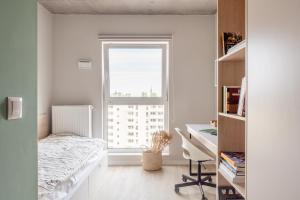 um quarto com uma cama, uma secretária e uma janela em Apartamenty Depot Wróblewskiego em Lódź