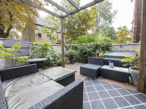 a patio with wicker furniture and a pergola at Pass the Keys West Didsbury Apartment w Garden sleeps 4 in Manchester