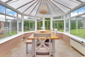 a conservatory with a table and chairs and windows at Pass the Keys Large family home in picturesque village in Westerham