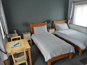 a room with two beds and a table and a window at Risley Guest House in Risley