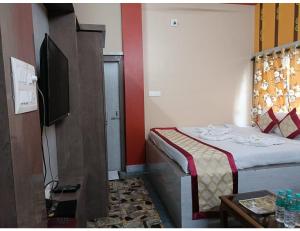 een kleine slaapkamer met een bed en een televisie bij EMBLIC HOTEL & RESTAURANT, Bolpur in Bolpur