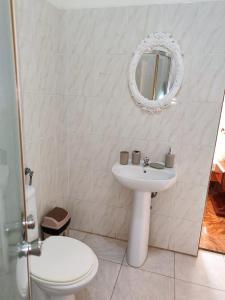 La salle de bains blanche est pourvue d'un lavabo et d'un miroir. dans l'établissement Casa Andrade Delgado - Rotxa Grande, à Ponta do Sol
