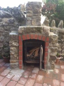 an outdoor brick fireplace with a stone wall at 1 Bed cottage The Stable at Llanrhidian Gower with sofa bed for additional guests in Swansea