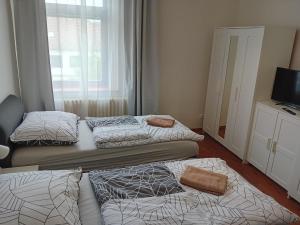 a room with three beds and a television and a window at Apartmány Šrámek Stříbro in Stříbro