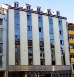 Un grand bâtiment blanc avec de nombreuses fenêtres dans l'établissement Hotel Rivoli, à Munich