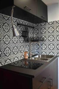a kitchen with a sink and black and white tiles at Charmant Studio au Cœur de Béthune in Béthune