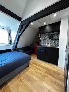 Cet appartement comprend une chambre avec un lit bleu et une cuisine. dans l'établissement Charmant Studio au Cœur de Béthune, à Béthune