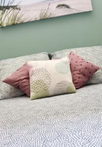 un grupo de almohadas sentadas en una cama en Appartement en rez-de-villa avec jardin, en Hyères