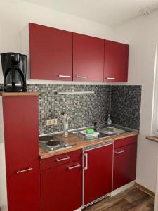 a kitchen with red cabinets and a sink at Ferienpark am Darß - Apartmenthaus 3 in Fuhlendorf