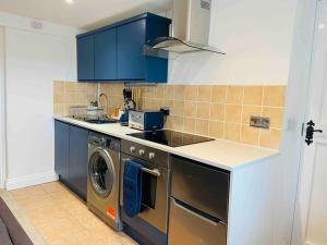 a kitchen with blue cabinets and a washing machine at The Mill Stylish Rural Apartment with Beautiful Views in Welsh Newton Common