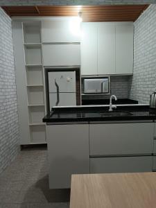 a kitchen with white cabinets and a sink and a microwave at Lapa Hostel - PARANÁ in Lapa