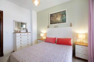 a bedroom with a bed with two red pillows at San jeronimo in Sanlúcar de Barrameda