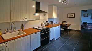 a kitchen with white cabinets and a sink and a stove at Doonreagan West Wing, Cashel in Canower
