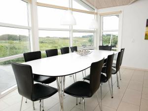 a white table and chairs in a room with windows at 8 person holiday home in L kken in Løkken
