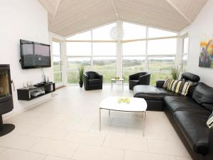 a living room with a black leather couch and a tv at 8 person holiday home in L kken in Løkken