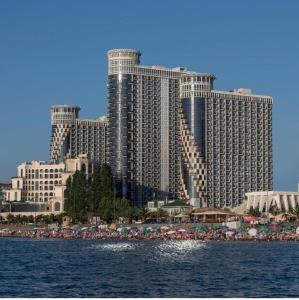 a large building with a beach in front of the water at Royal Apartments in Batumi