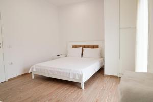 um quarto branco com uma cama branca e paredes brancas em Mega Hotel em Gjirokastër
