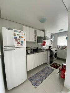 a white kitchen with a refrigerator and a stove at Vista Panorâmica com piscina in Porto Alegre
