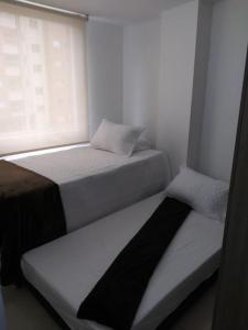 2 Betten in einem kleinen Zimmer mit Fenster in der Unterkunft MALAGA in Sabaneta