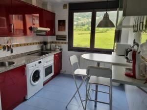 cocina con armarios rojos, fregadero y lavavajillas en Piso zona hospital 7 personas, en Oviedo