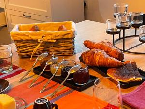 una mesa con pan y cruasanes y una cesta de comida en La Part des Anges - Maison d'hôtes et Table épicurienne, en Penmarch