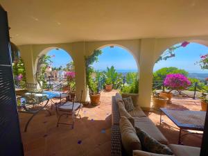 eine Terrasse mit einem Sofa, Tischen und Fenstern in der Unterkunft Boutique Hotel Maravilla - Marbella in Benahavís