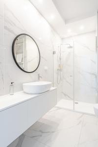 een witte badkamer met een wastafel en een spiegel bij RentPlanet - Apartamenty Księcia Witolda in Wrocław