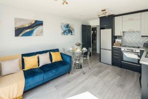 ein Wohnzimmer mit einem blauen Sofa und einer Küche in der Unterkunft Smart Living Sophisticated Style - Photo ID & Deposit Required in London