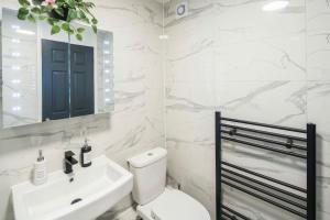 a bathroom with a white toilet and a sink at Smart Living Sophisticated Style - Photo ID & Deposit Required in London