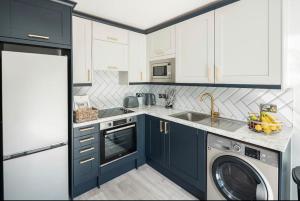 a kitchen with blue cabinets and a washing machine at Smart Living Sophisticated Style - Photo ID & Deposit Required in London