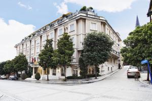 un gran edificio blanco en una calle con árboles en Eresin Hotels Sultanahmet - Boutique Class, en Estambul